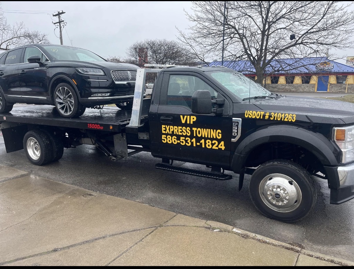 VIP Express Towing flatbed truck transporting a vehicle in Michigan